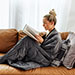 Woman reading a book wrapped up in a weighted blanket